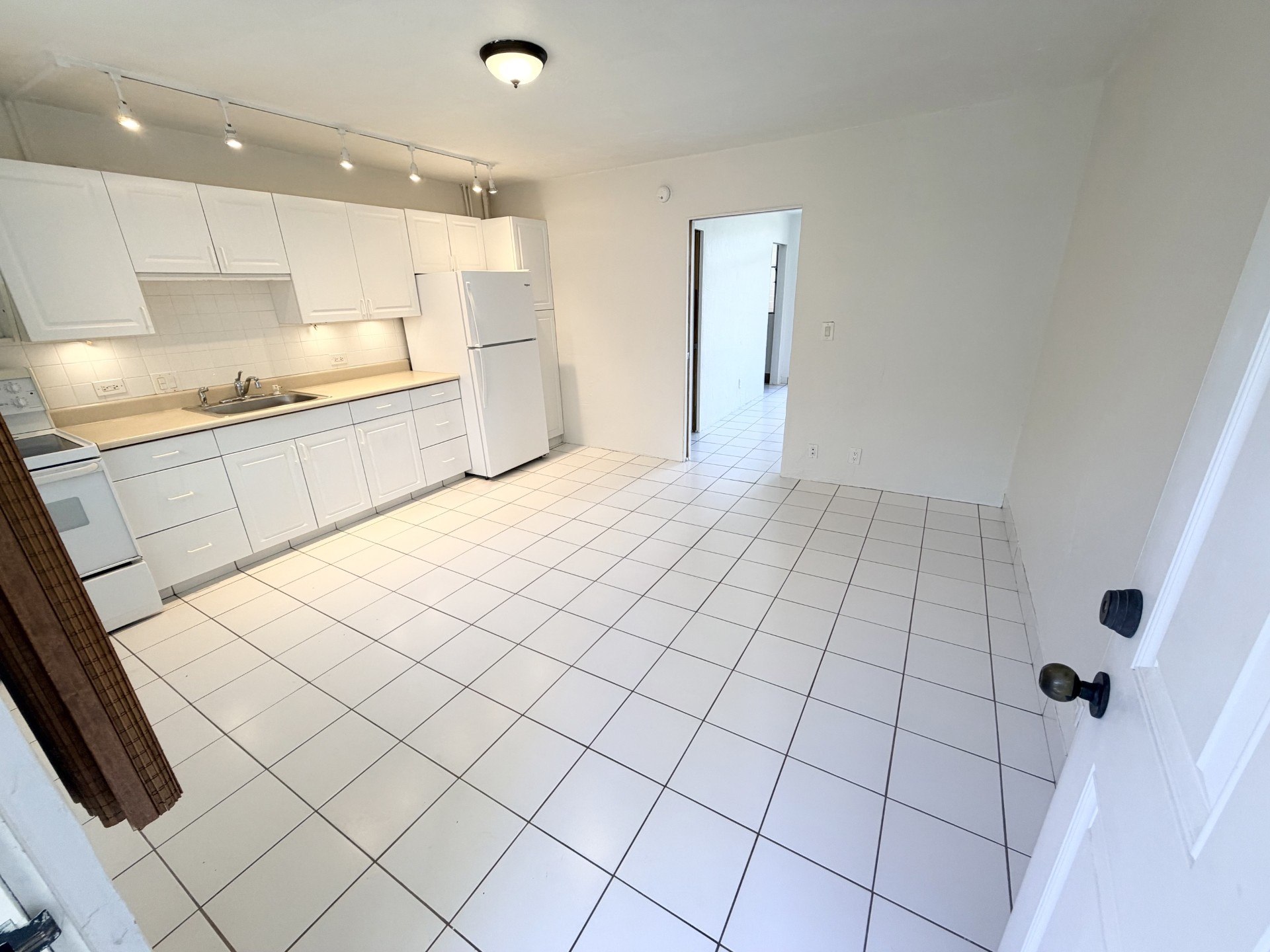A kitchen with white tile flooring and white appliances.
